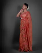 Side view of a model showcasing Red Crushed Tissue Silk Saree With Cutwork Embroidery, Ideal for occasions like engagements or baby showers By Mirra Clothing