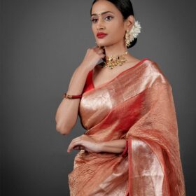"Close-up of an orange crushed tissue silk saree, highlighting its unique crinkle effect."By Mirra Clothing