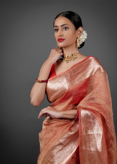 "Close-up of an orange crushed tissue silk saree, highlighting its unique crinkle effect."By Mirra Clothing