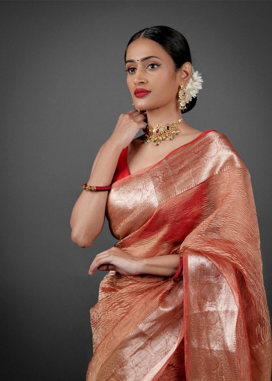 "Close-up of an orange crushed tissue silk saree, highlighting its unique crinkle effect."By Mirra Clothing