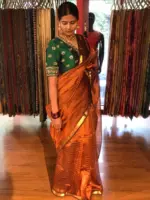 Close up view of a model showcasing Honey Orange Mangalagiri Silk Saree Handwoven in Gold Zari Chequered Pattern, Suitable For Formal Events & Anniversaries By Mirra Clothing