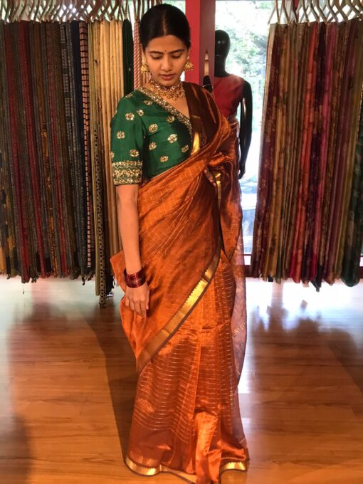 Close up view of a model showcasing Honey Orange Mangalagiri Silk Saree Handwoven in Gold Zari Chequered Pattern, Suitable For Formal Events & Anniversaries By Mirra Clothing