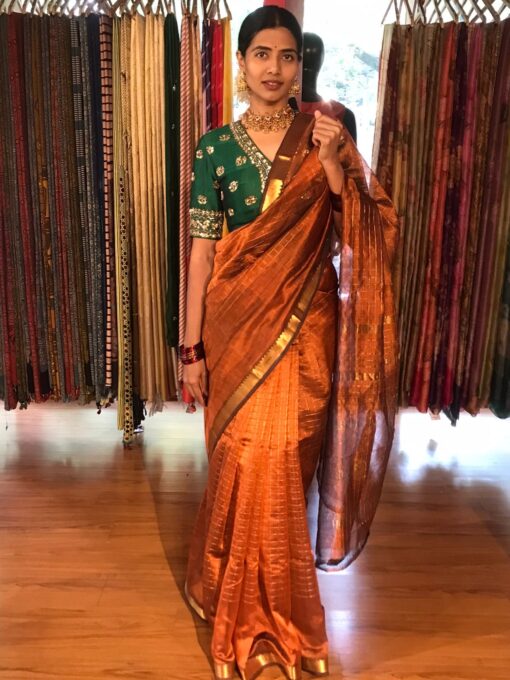 Side view of a model showcasing Honey Orange Mangalagiri Silk Saree Handwoven in Gold Zari Chequered Pattern, Suitable For Traditional Office Events or Award Functions By Mirra Clothing