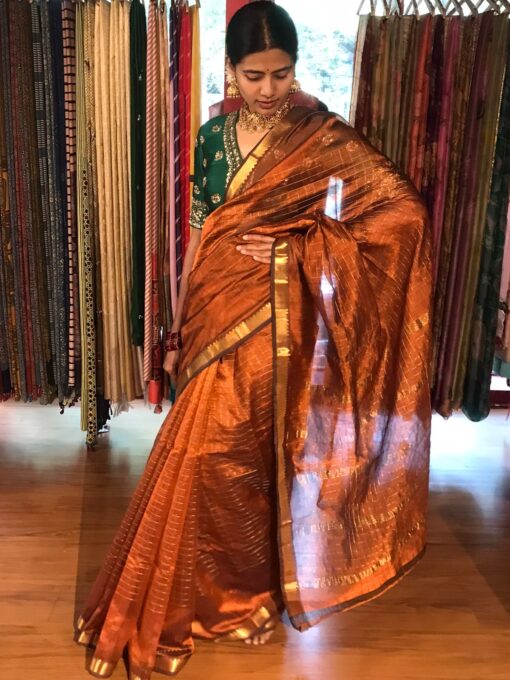 Side view of a model showcasing Honey Orange Mangalagiri Silk Saree Handwoven in Gold Zari Chequered Pattern, Suitable For Cultural Gatherings & Temple Visits By Mirra Clothing