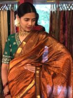 "Front view of a model showcasing a Honey Orange Mangalagiri Silk Saree Handwoven in Gold Zari Chequered Pattern, Suitable For Engagement or Sangeet Functions By Mirra Clothing